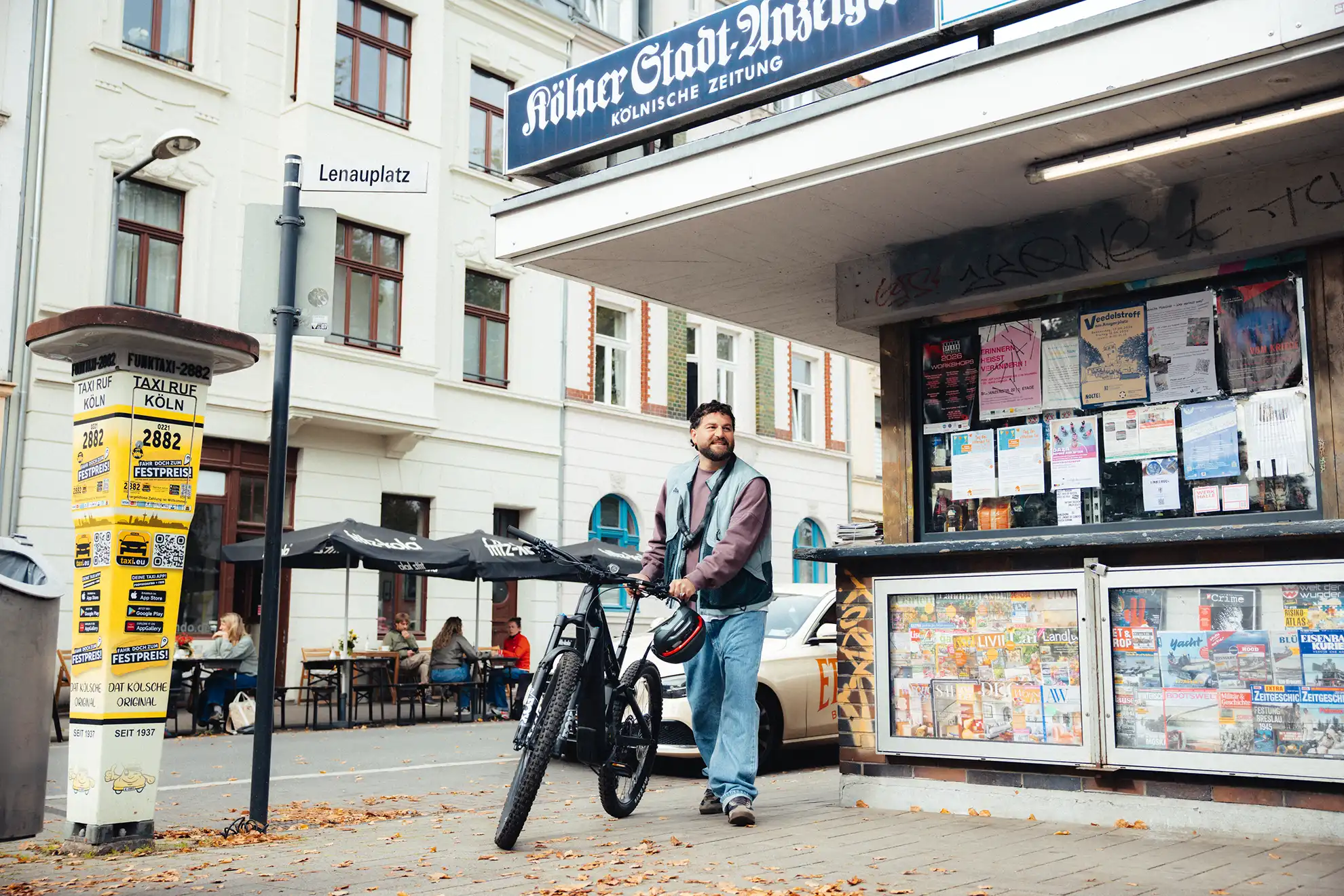 Ein Mann schiebt sein Dienstrad an einem Kiosk vorbei